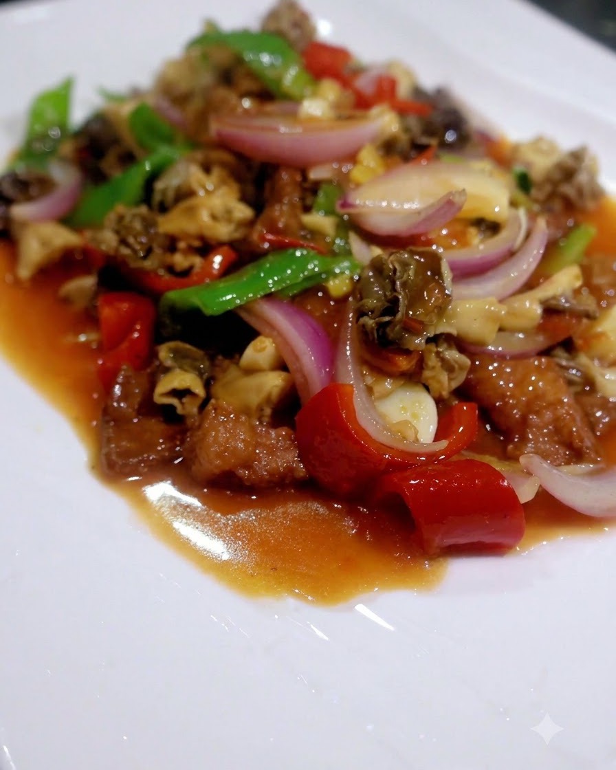 A finished stir-fry of mixed mushrooms, peppers, bok choy, and meat served on a white plate.