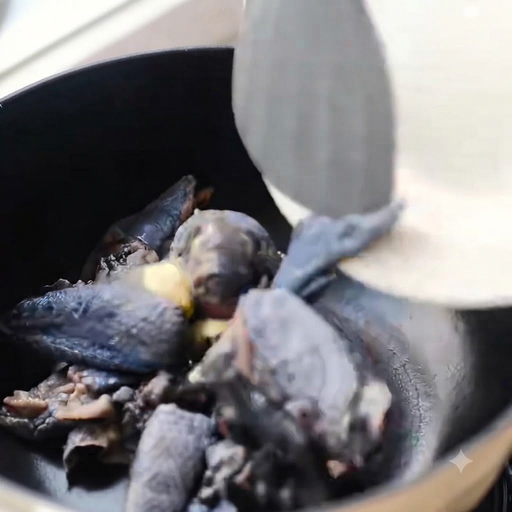Black-skinned chicken pieces being stir-fried in a black pot with ginger.