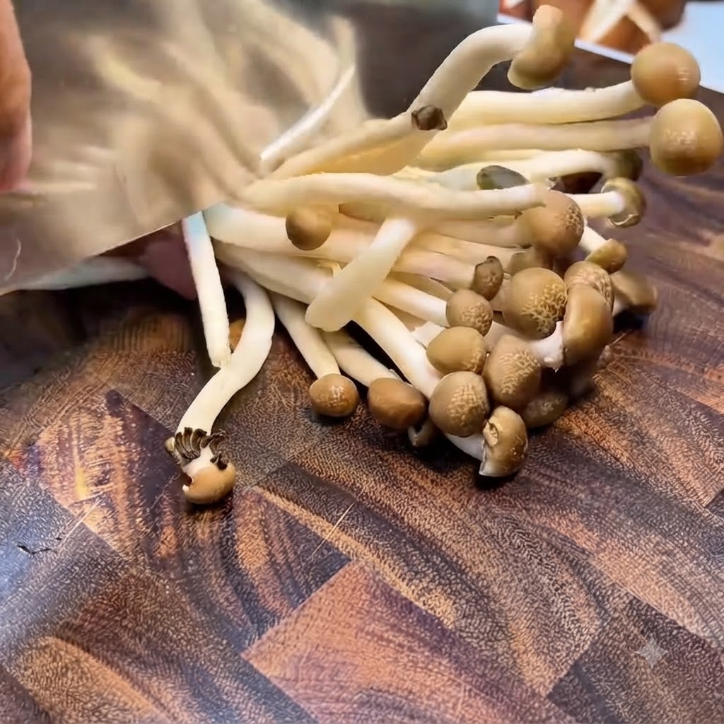 Shimeji mushrooms being trimmed at the root cluster with a cleaver on a wooden board.