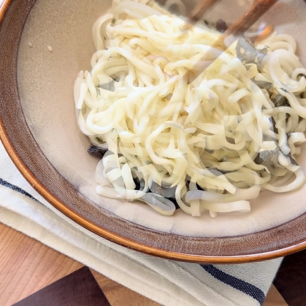 Hot mushroom soup being poured from above onto the noodles inside the serving bowl.