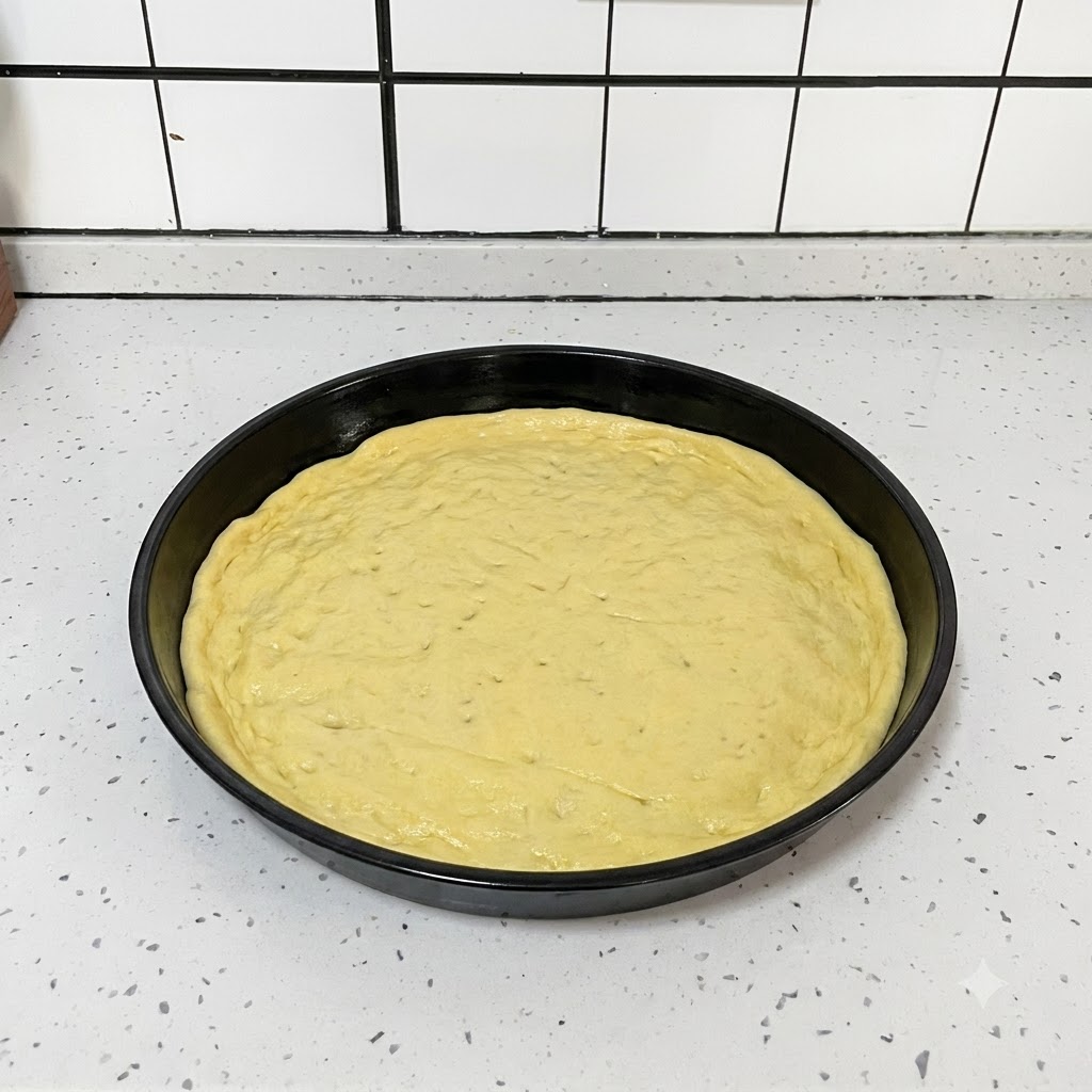 A black kitchen tool being used to poke small holes uniformly across a flattened round pizza dough inside a black pan.