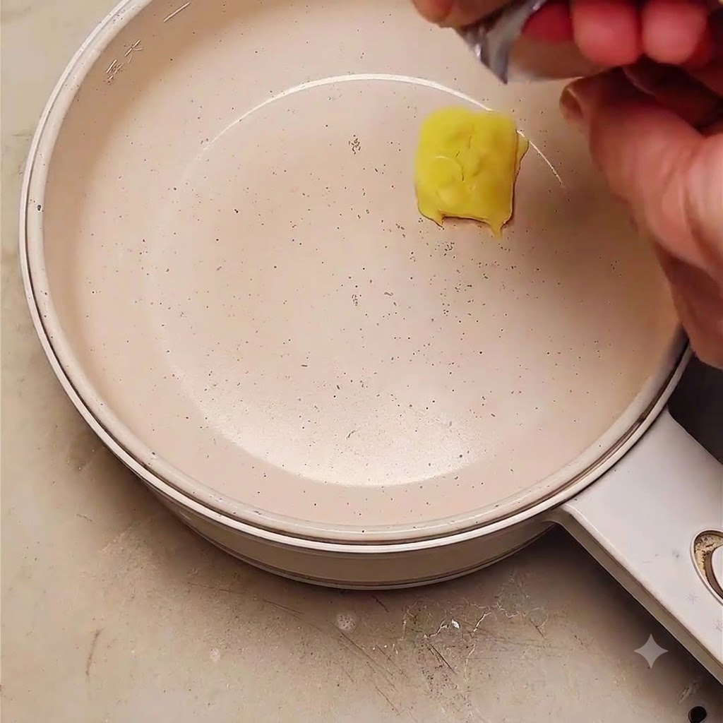 A pat of butter melting in a frying pan with sliced red onions being added.