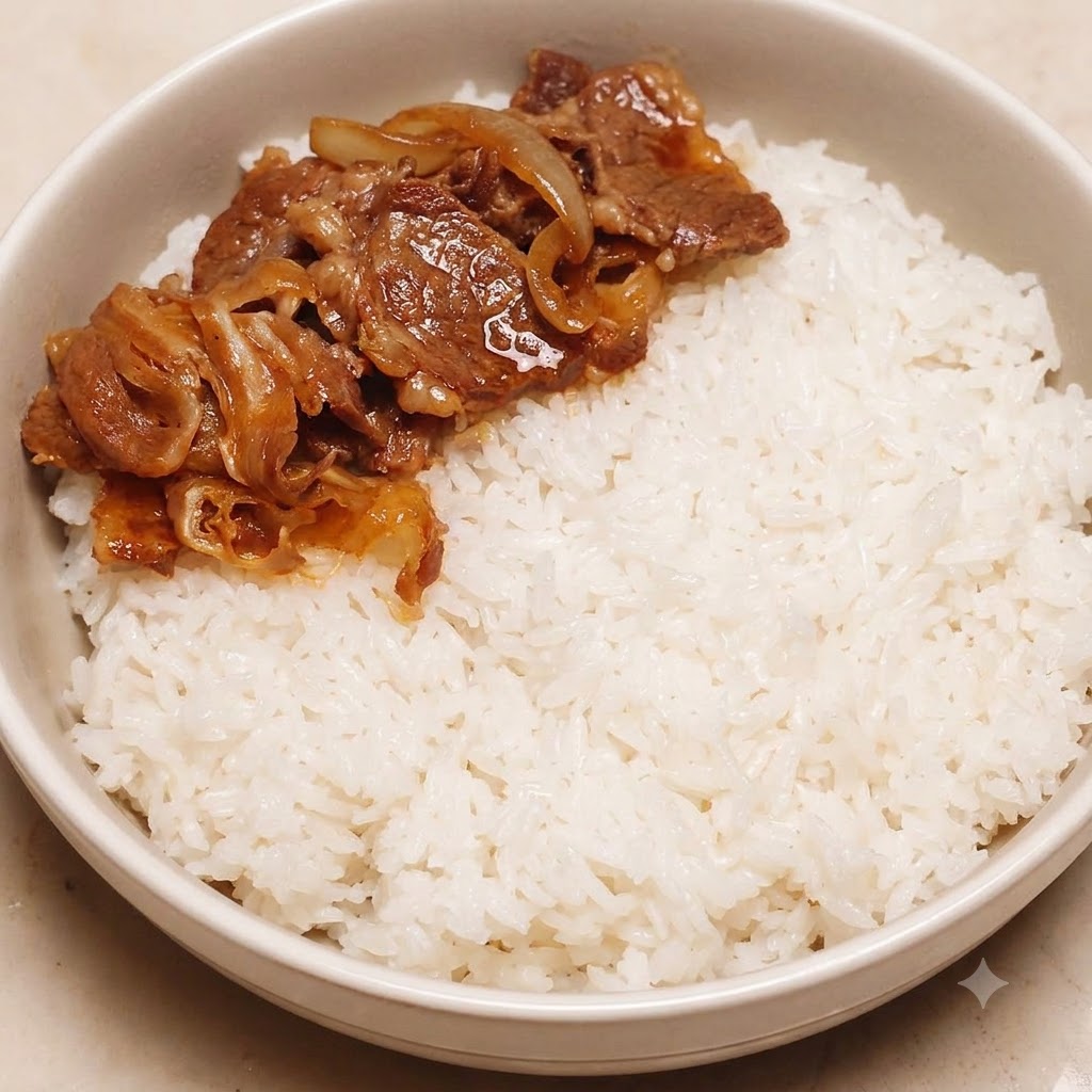 Cooked beef and onions placed neatly on one side of a bowl filled with white rice.