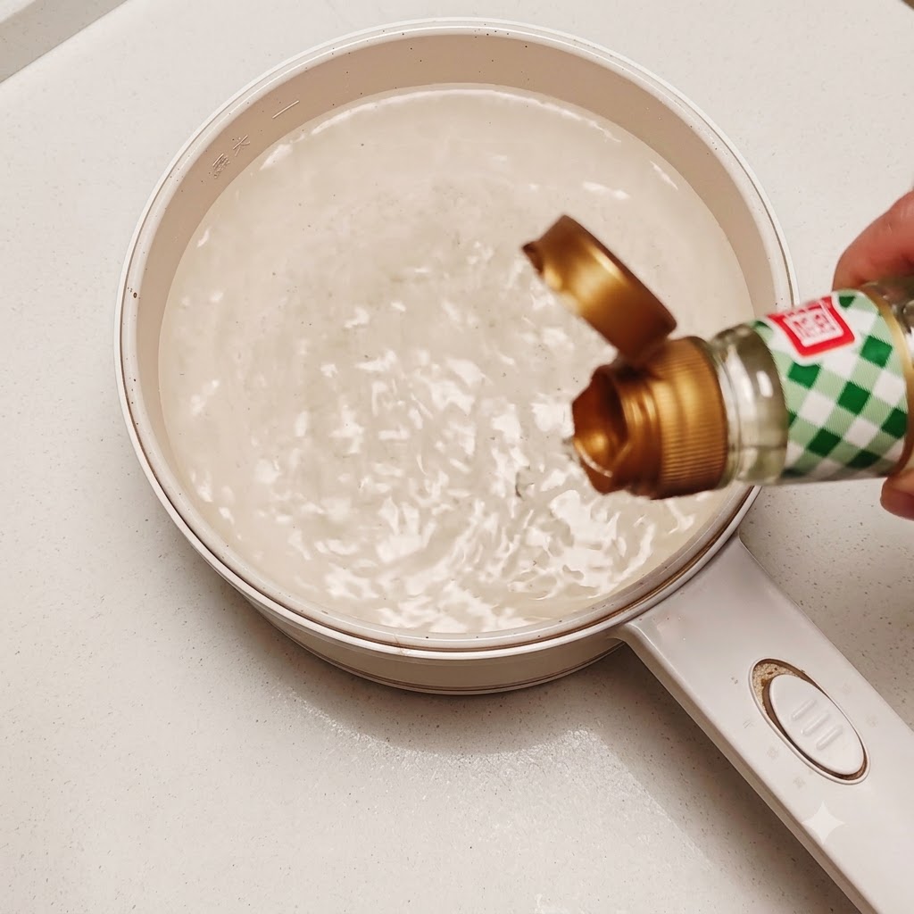 An edible raw egg being dropped into a pot of swirling hot water with a little rice vinegar.