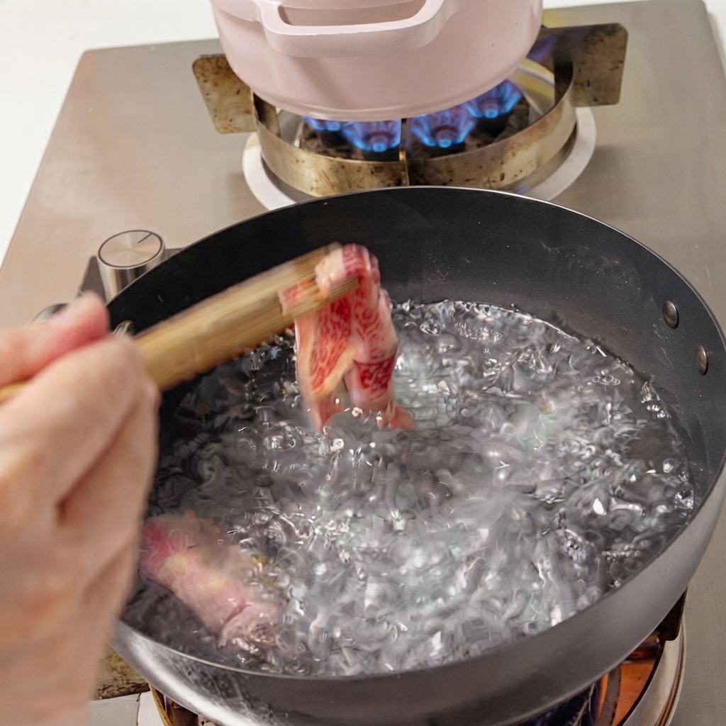 Fresh beef slices being dropped into a pot of boiling water with chopsticks.