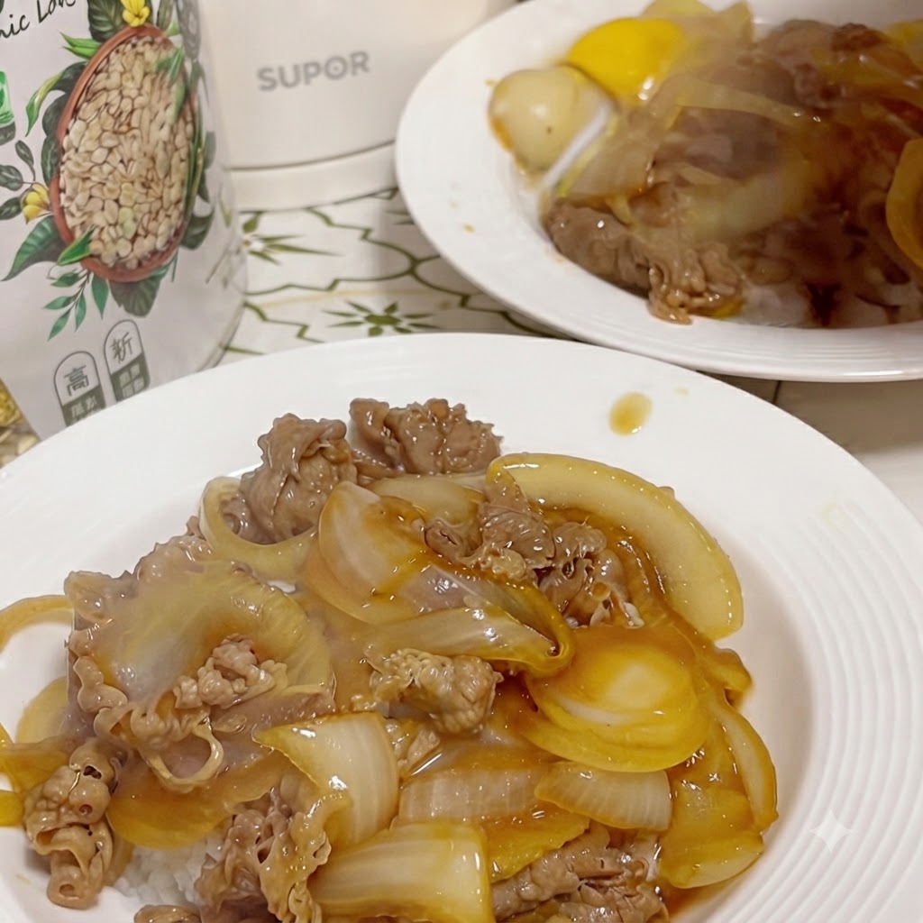 A finished plate of beef and onion over rice, with a cracked raw egg yolk sitting in a small well created in the center, and a second plate visible in the background.