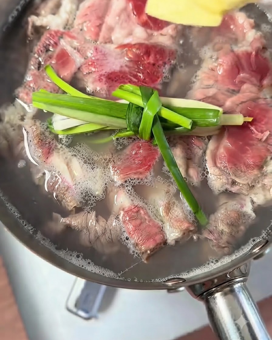 Scallion knots and ginger pieces floating in a pot of boiling beef.