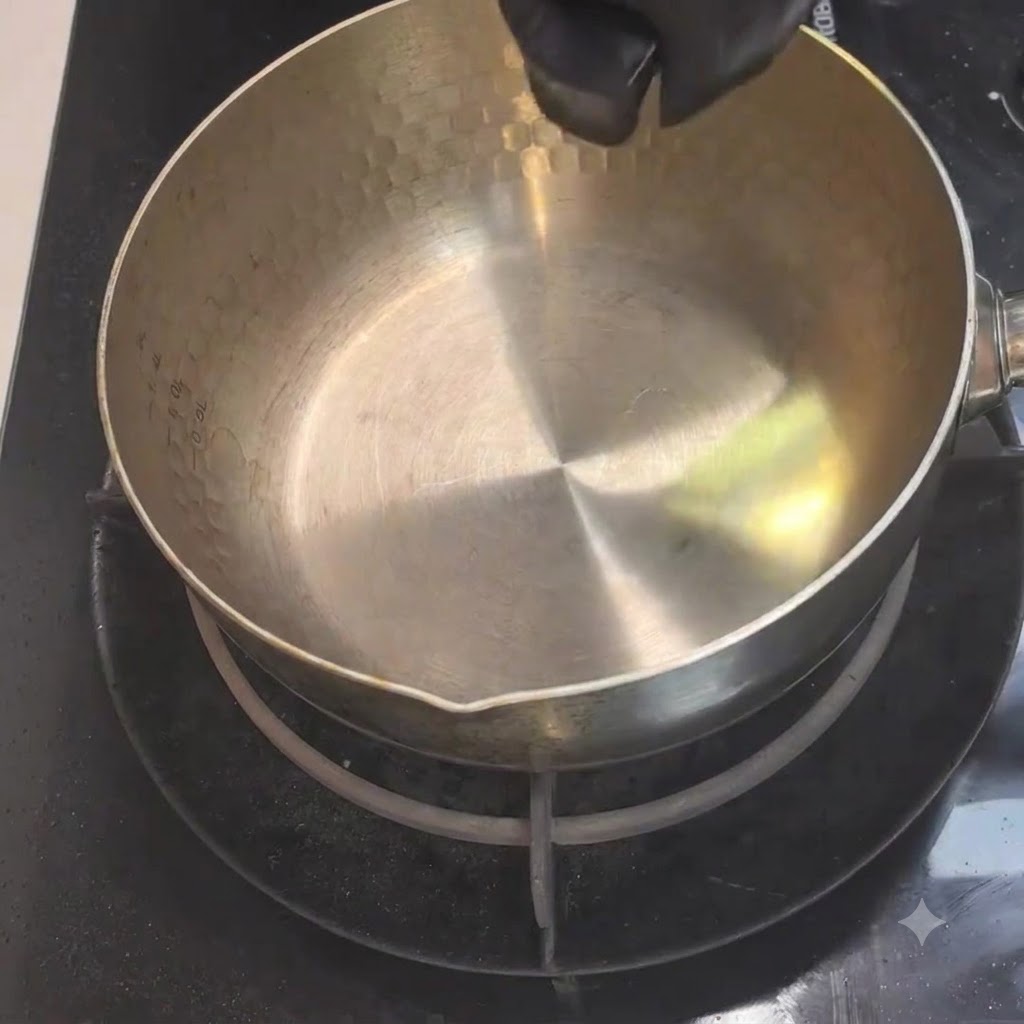 Cooking oil being poured from a small container into a heated metal pot on the stove.