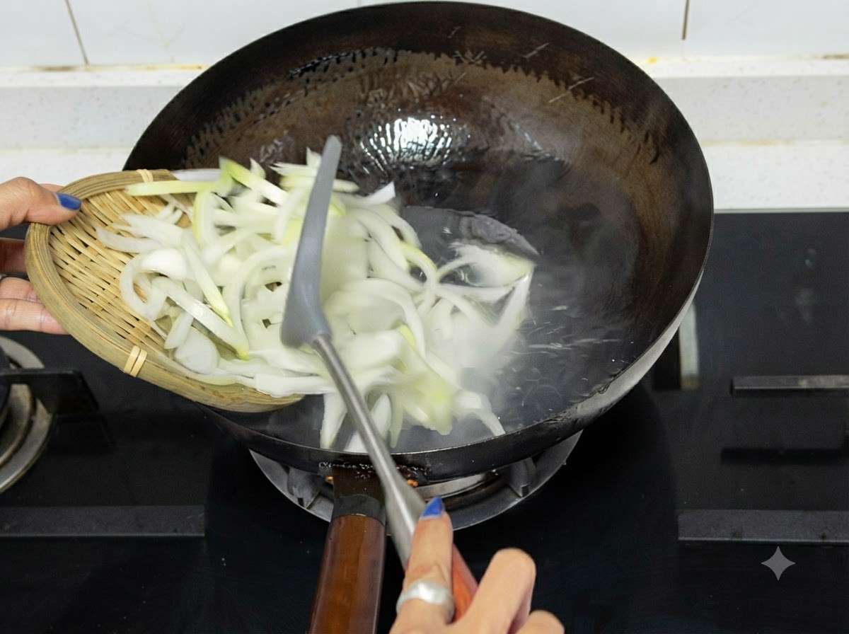 Sliced onions being emptied from a wooden tray into a hot wok on a stovetop.
