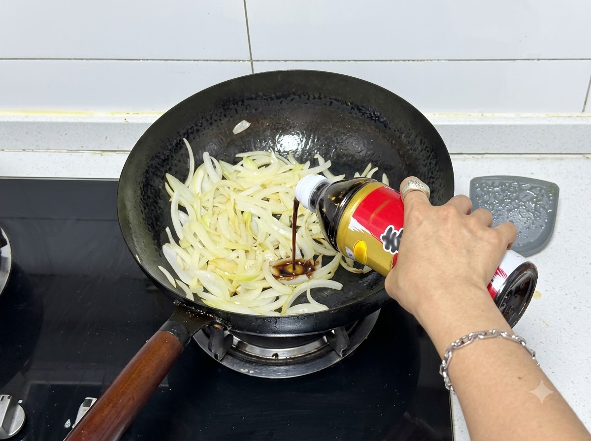 Sukiyaki sauce being squeezed from a bottle into a wok filled with stir-fried onions.