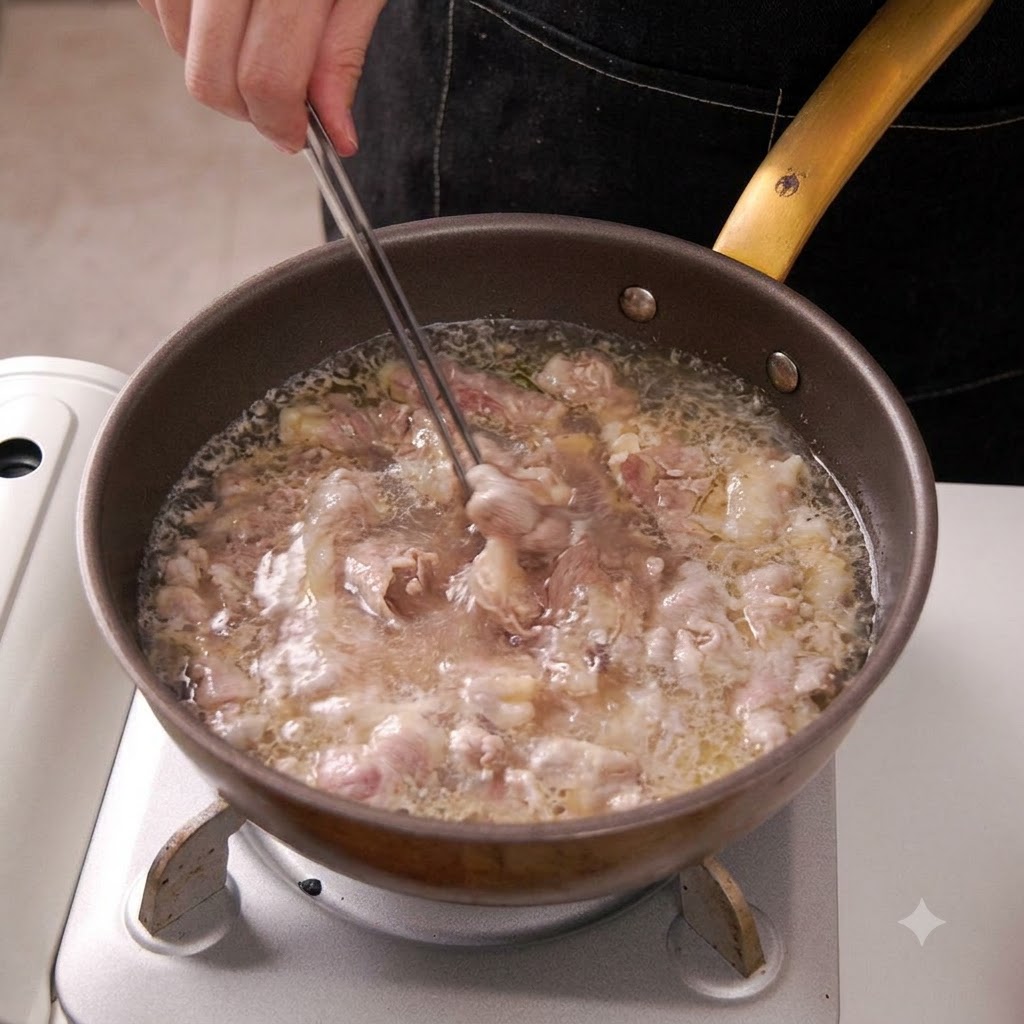 Tongs lifting blanched beef slices out of boiling water in a pan.