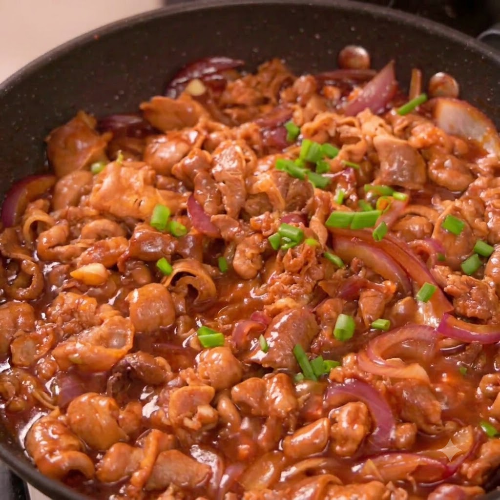 Chopped green onion pieces scattered over cooked beef and red onions inside a frying pan.