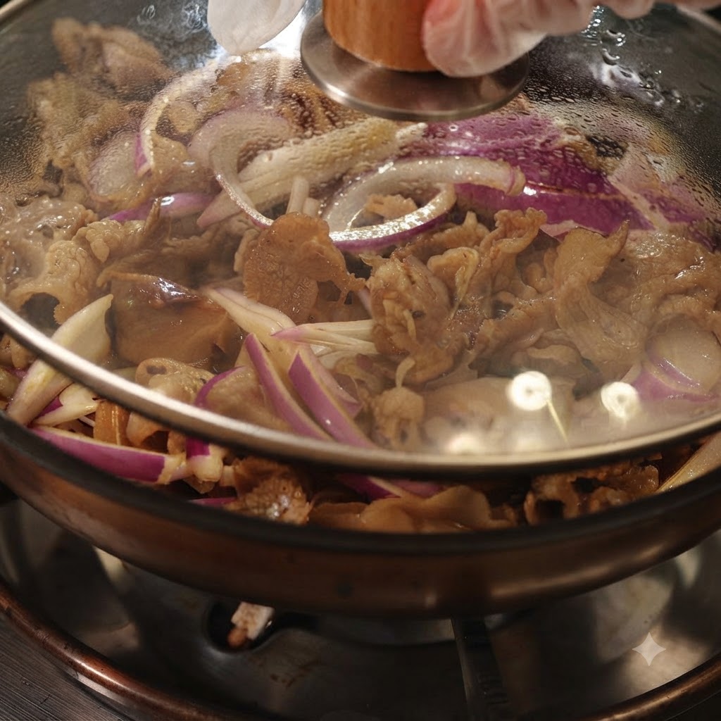 A pan covered with a clear glass lid, showing simmering beef and red onions inside.