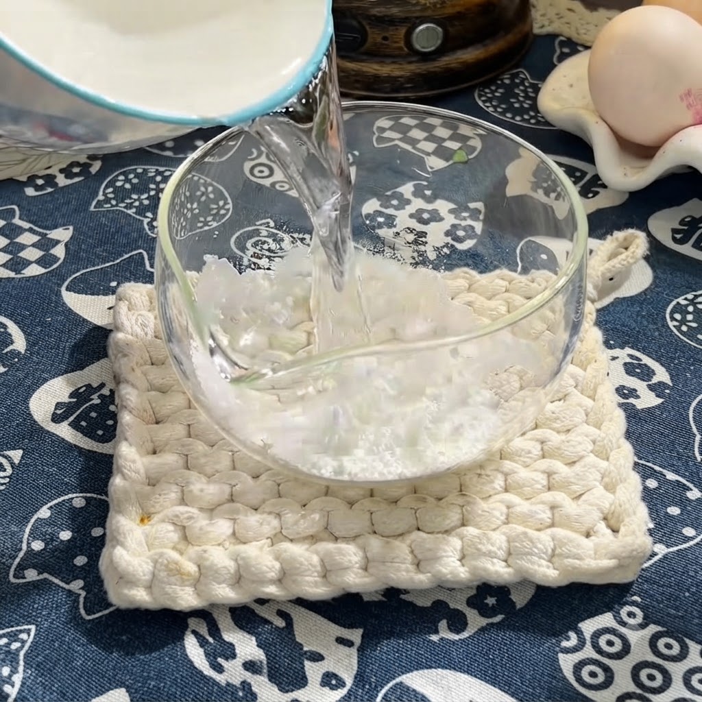 Water being poured into a bowl of cornstarch to form a liquid base.