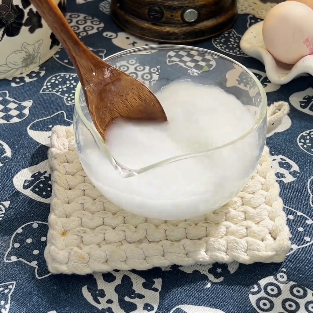 A wooden spoon stirring soy sauce, oyster sauce, and honey into the cornstarch mixture.