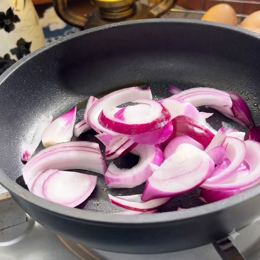 Red onion and beef slices cooking in a frying pan.