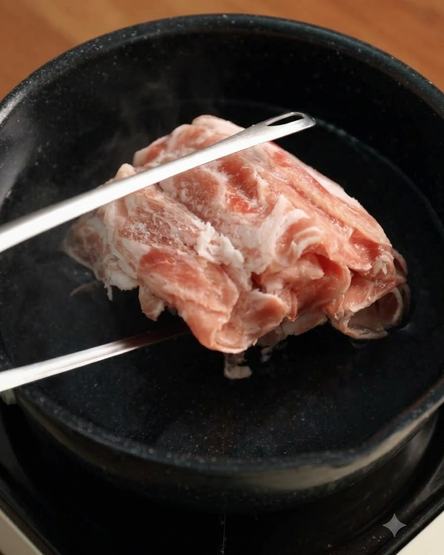 Frozen beef slices lowered into boiling water with metal tongs.