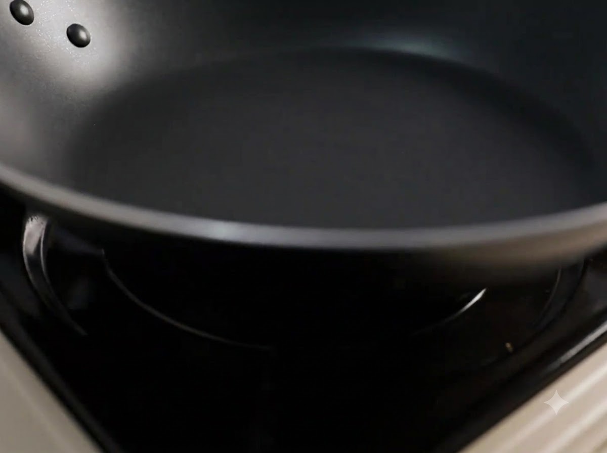 Cooking oil being poured into a heated black frying pan.