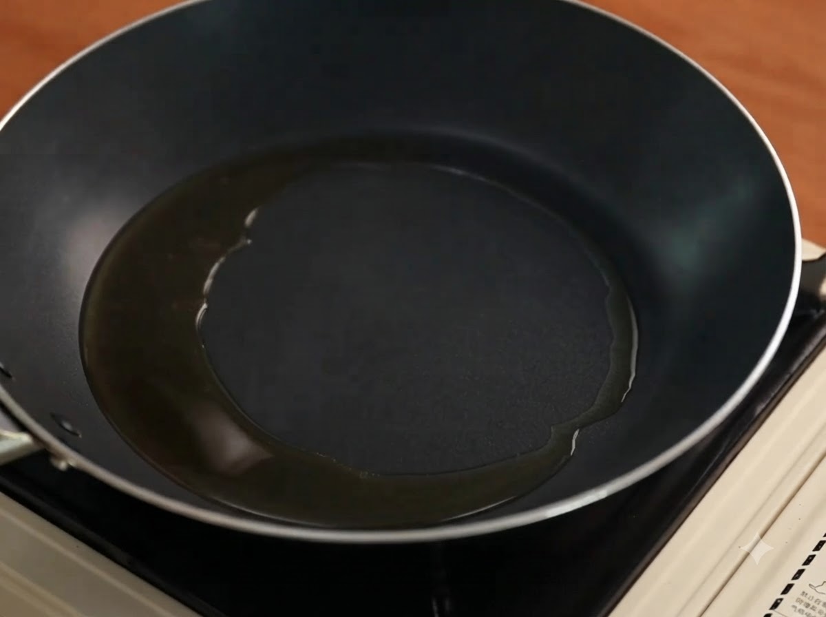 Sliced red onions cooking and sizzling in an oiled frying pan.