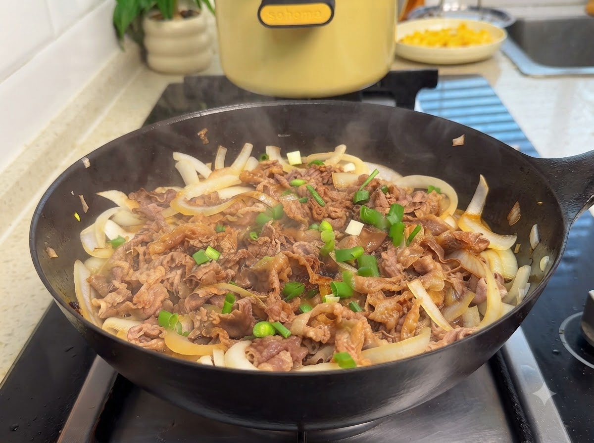 Chopped green onions and sesame seeds falling over a sizzling pan of beef and onions.
