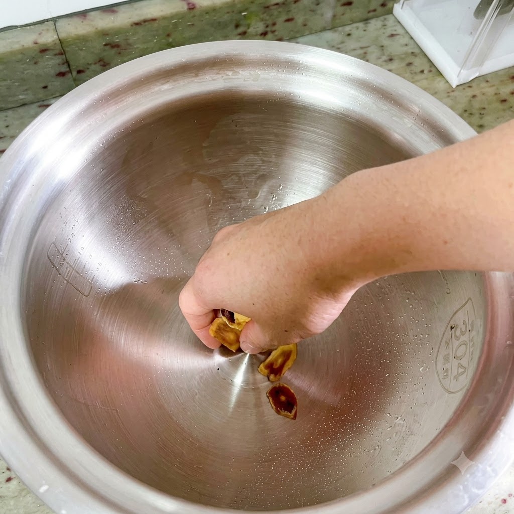 A hand placing sliced Korean ginseng into the bottom of a large, empty metal pot.