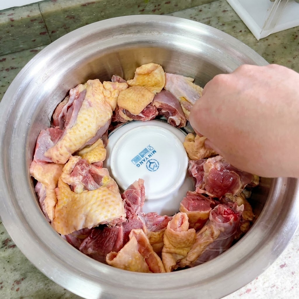 Raw duck pieces arranged tightly in a ring around the upside-down ceramic bowl inside the metal pot.