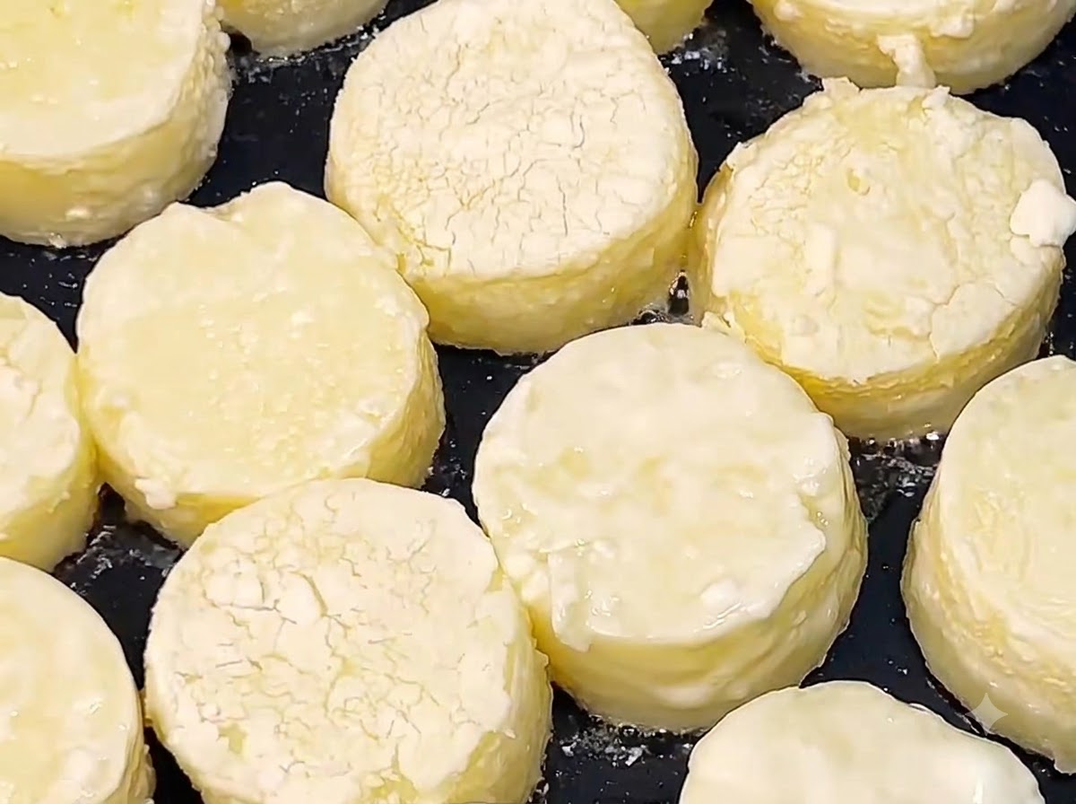 Japanese tofu rounds frying in hot oil in a black skillet until the surfaces turn golden brown.