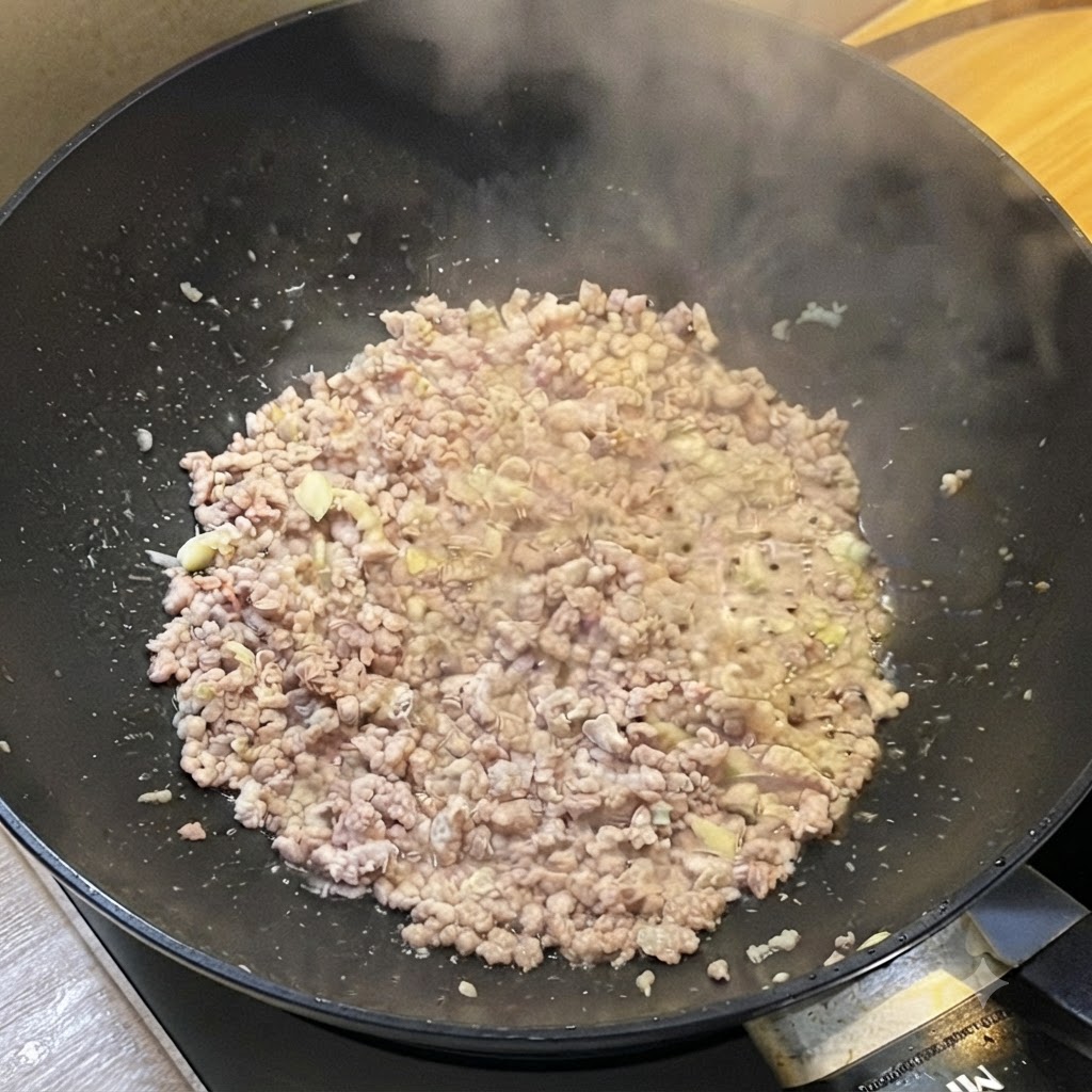 A wok filled with browned minced meat releasing steam while being seasoned with liquid sauces.