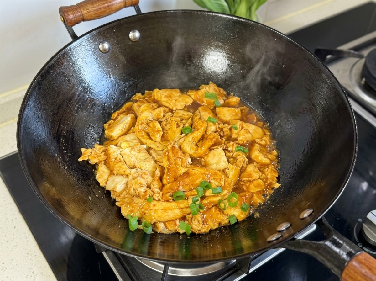 Chopped green onions sprinkled on top of the cooked tofu and egg mixture in a black wok.