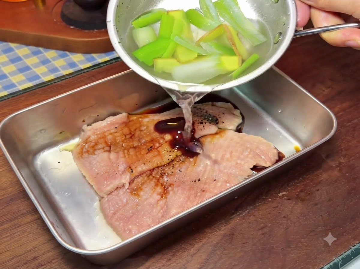 A small bowl pouring liquid over pork cutlets inside a larger metal container during preparation.