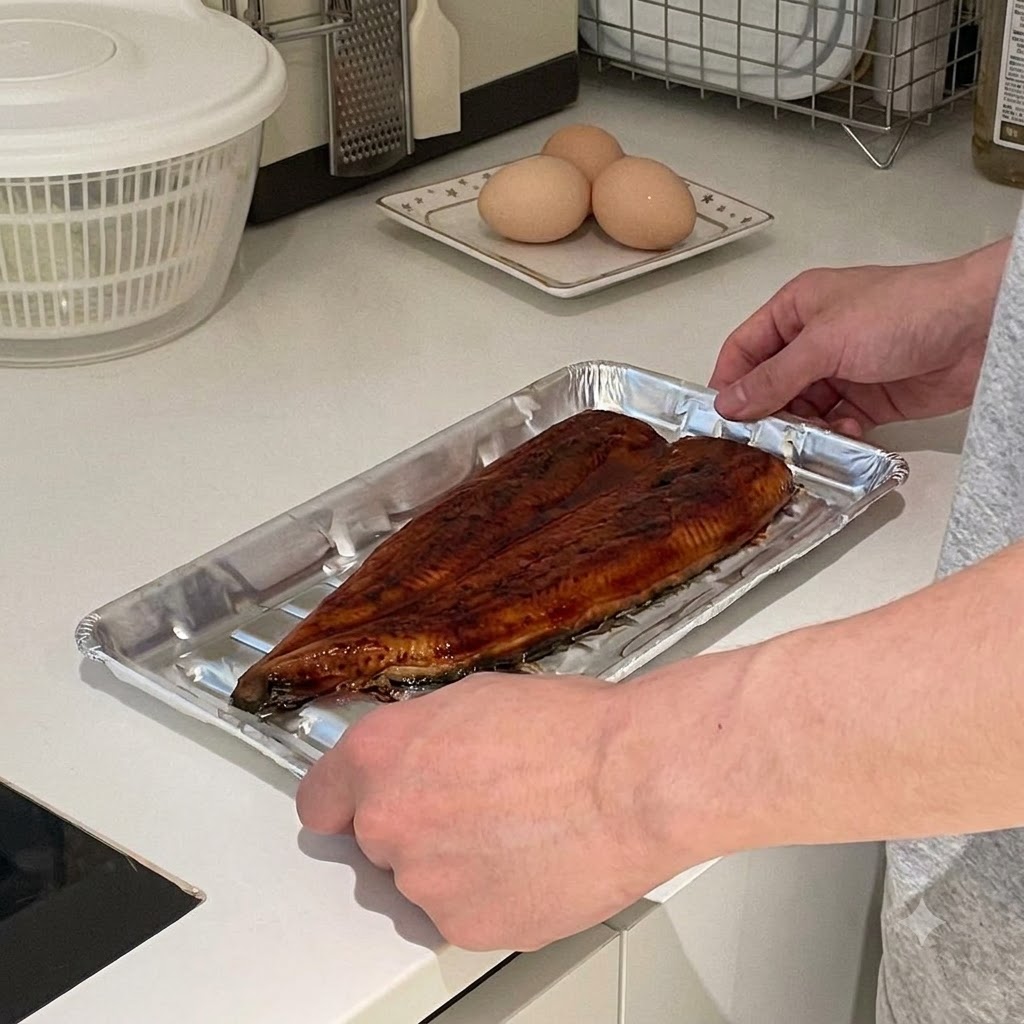 A pair of hands carefully opening aluminum foil to reveal a large, glazed piece of eel.
