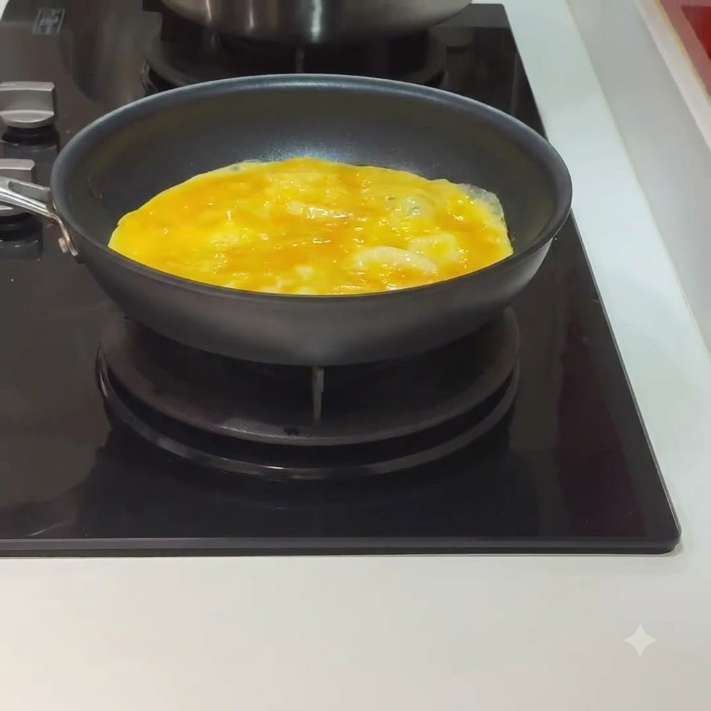An egg cooking and beginning to set inside a black pan on a stovetop.