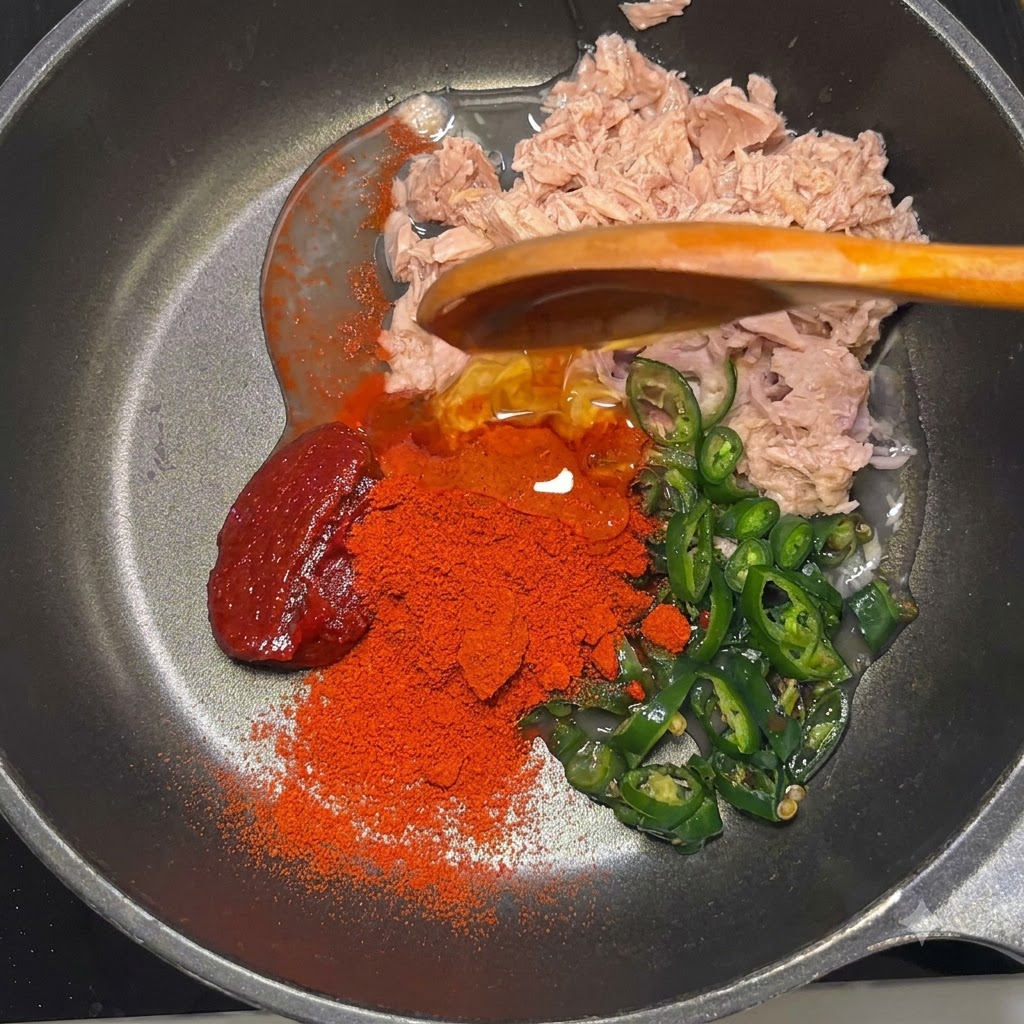 Gochujang paste, red gochugaru powder, corn syrup, and mayonnaise sitting in the pan over the tuna and peppers.