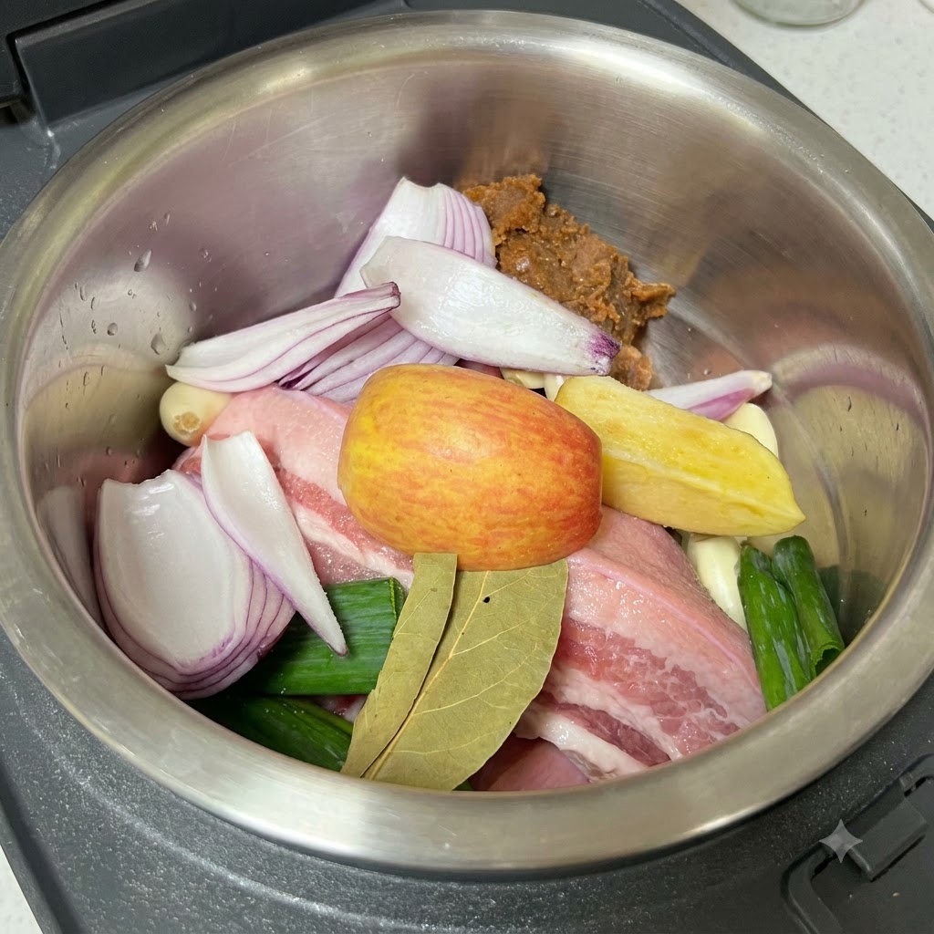 Salt being ground over the raw pork belly, aromatics, and soybean paste inside the cooking pot.