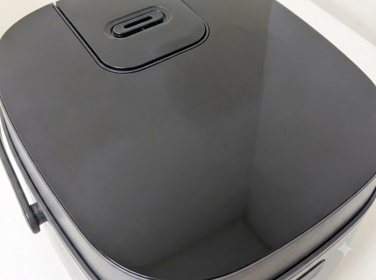 The exterior lid of a modern black digital rice cooker.