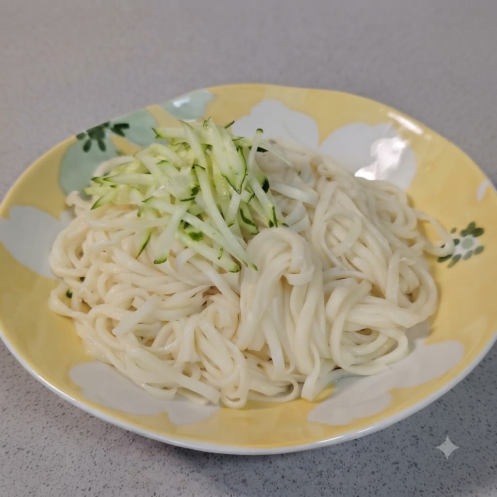 A small mound of fresh green shredded cucumber being placed on top of white boiled noodles in a decorative plate.