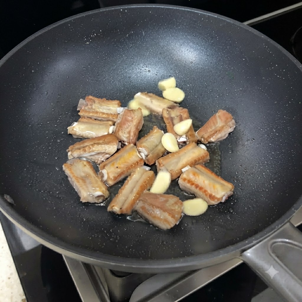 Slices of garlic scattered among the searing pork ribs in the skillet.
