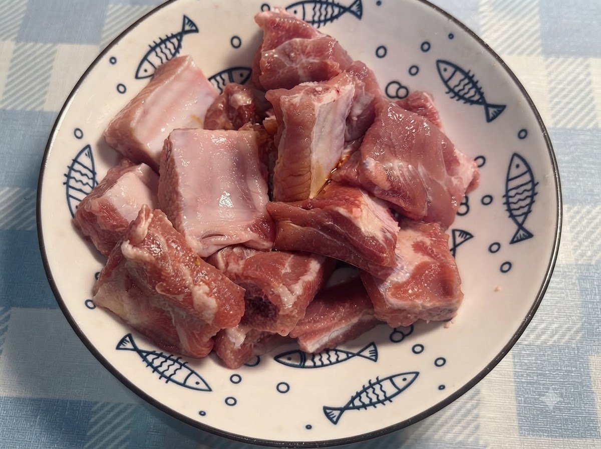 Gloved hands tossing and mixing the seasoned pork ribs in a white plate.