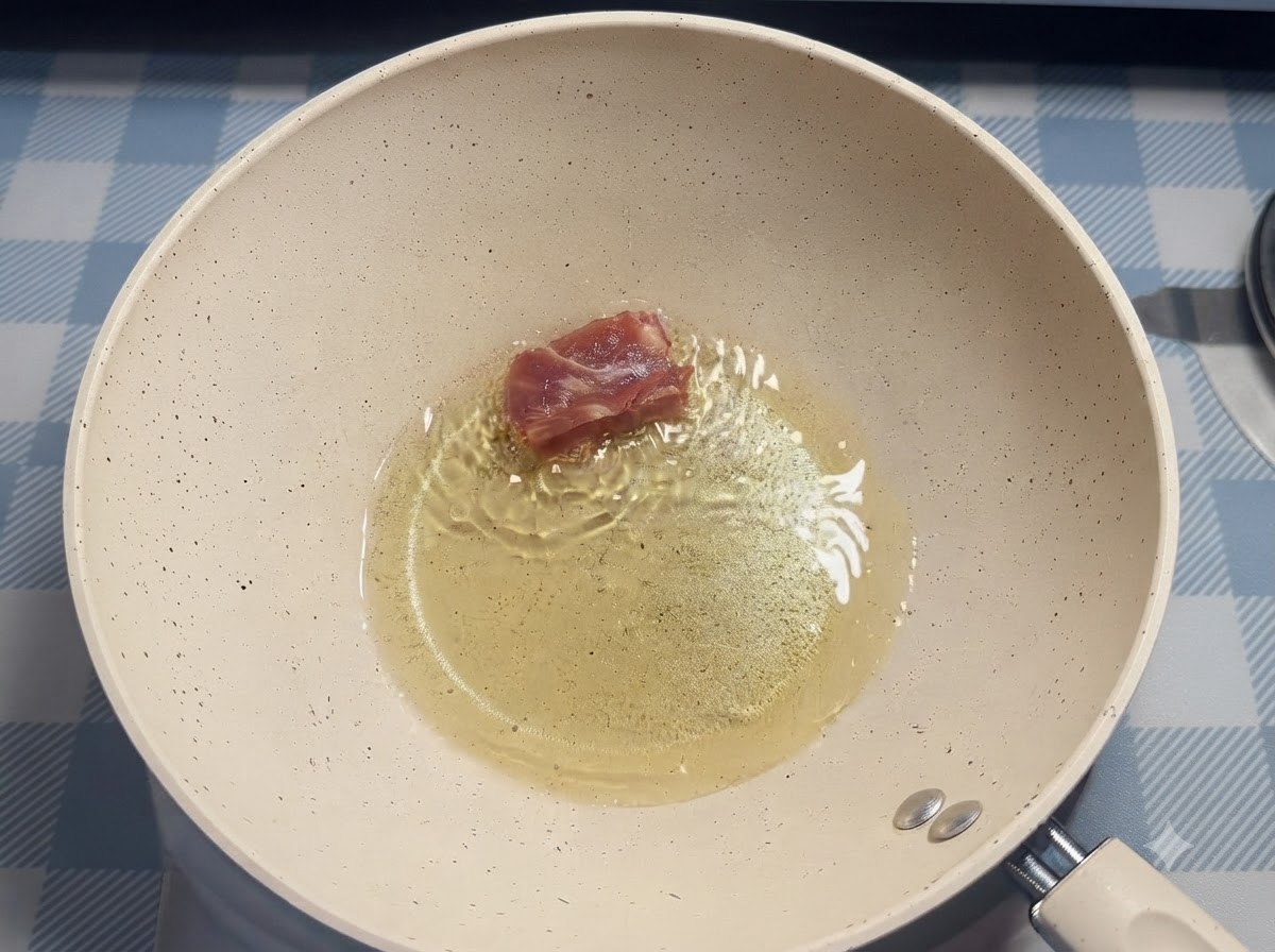 A single piece of pork rib being placed into hot oil inside a white frying pan using chopsticks.