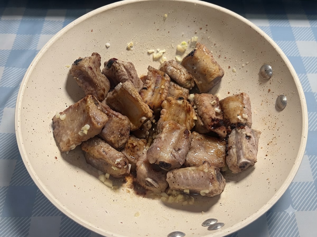 A pinch of salt being sprinkled directly over the pan-fried pork ribs.
