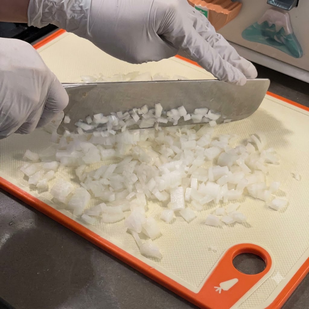 Finely diced white onions cooking down in a hot cast-iron skillet.