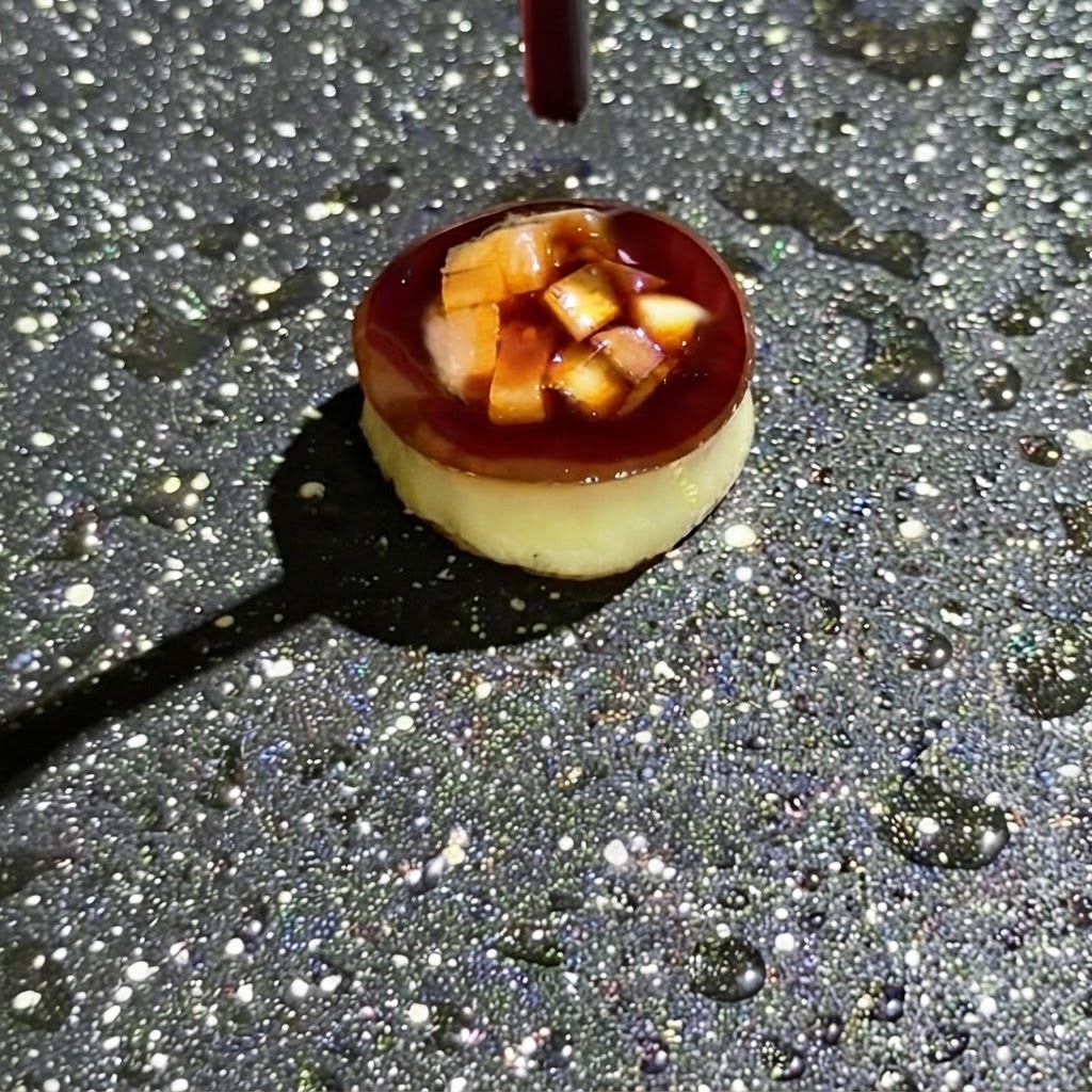 A dropper releasing dark soy sauce over diced ingredients stuffed inside a small round cooking mold in a pan.