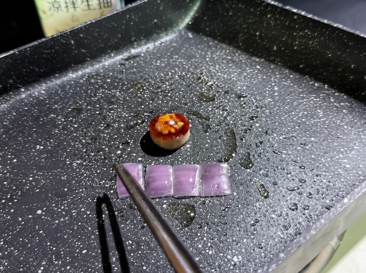 Four small rectangular slices of purple onion frying in an oiled pan alongside the filled mushroom ring.