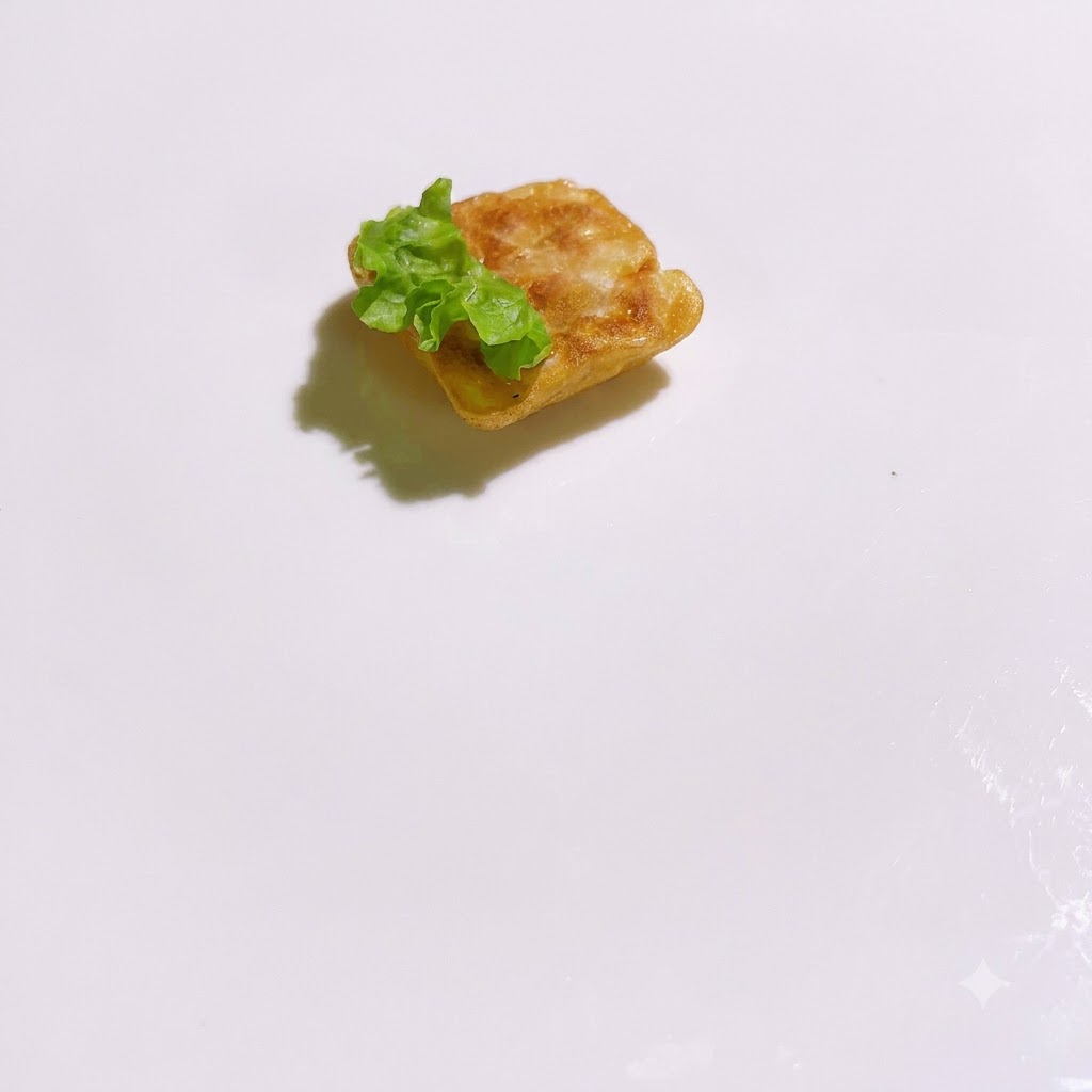 Fresh green lettuce pieces arranged around a cooked square base on a white plate.