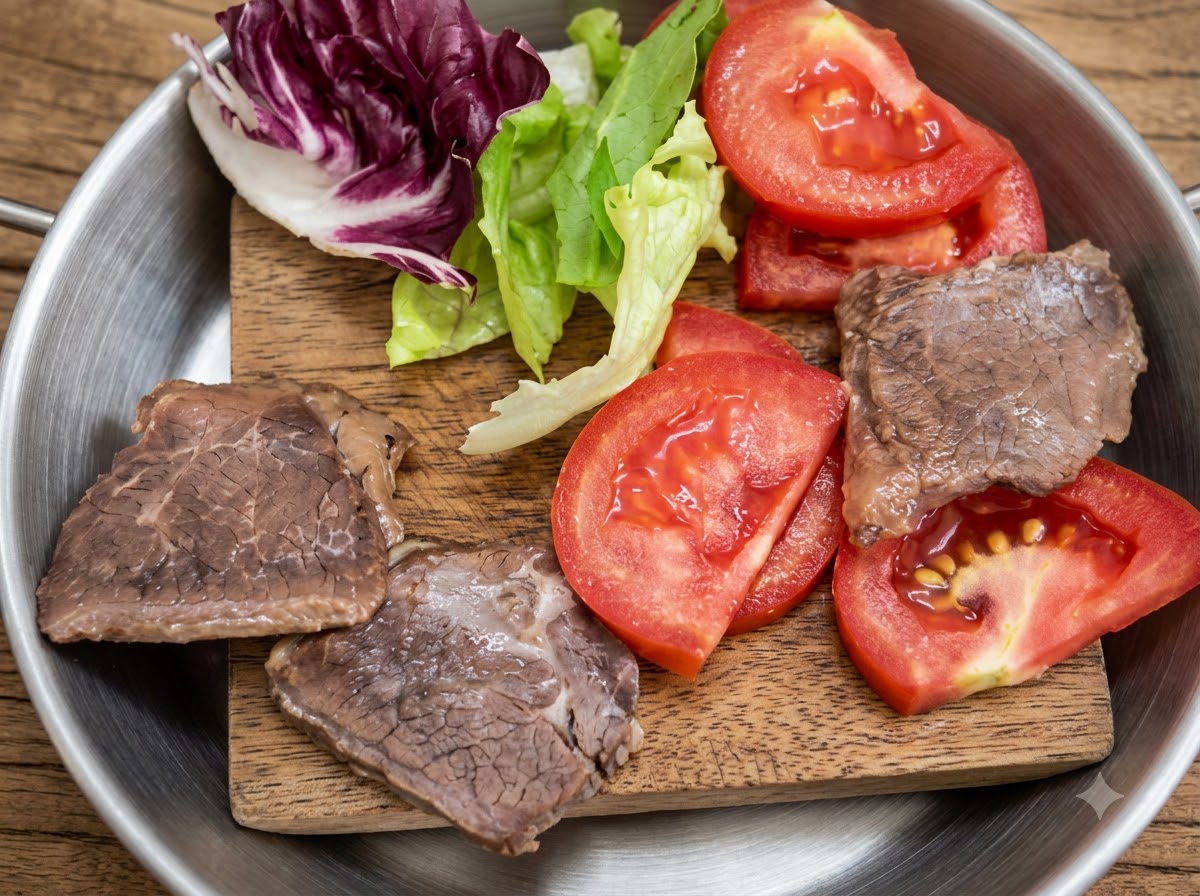 Fresh lettuce, sliced tomatoes, and cooked meat pieces arranged on a small wooden board.