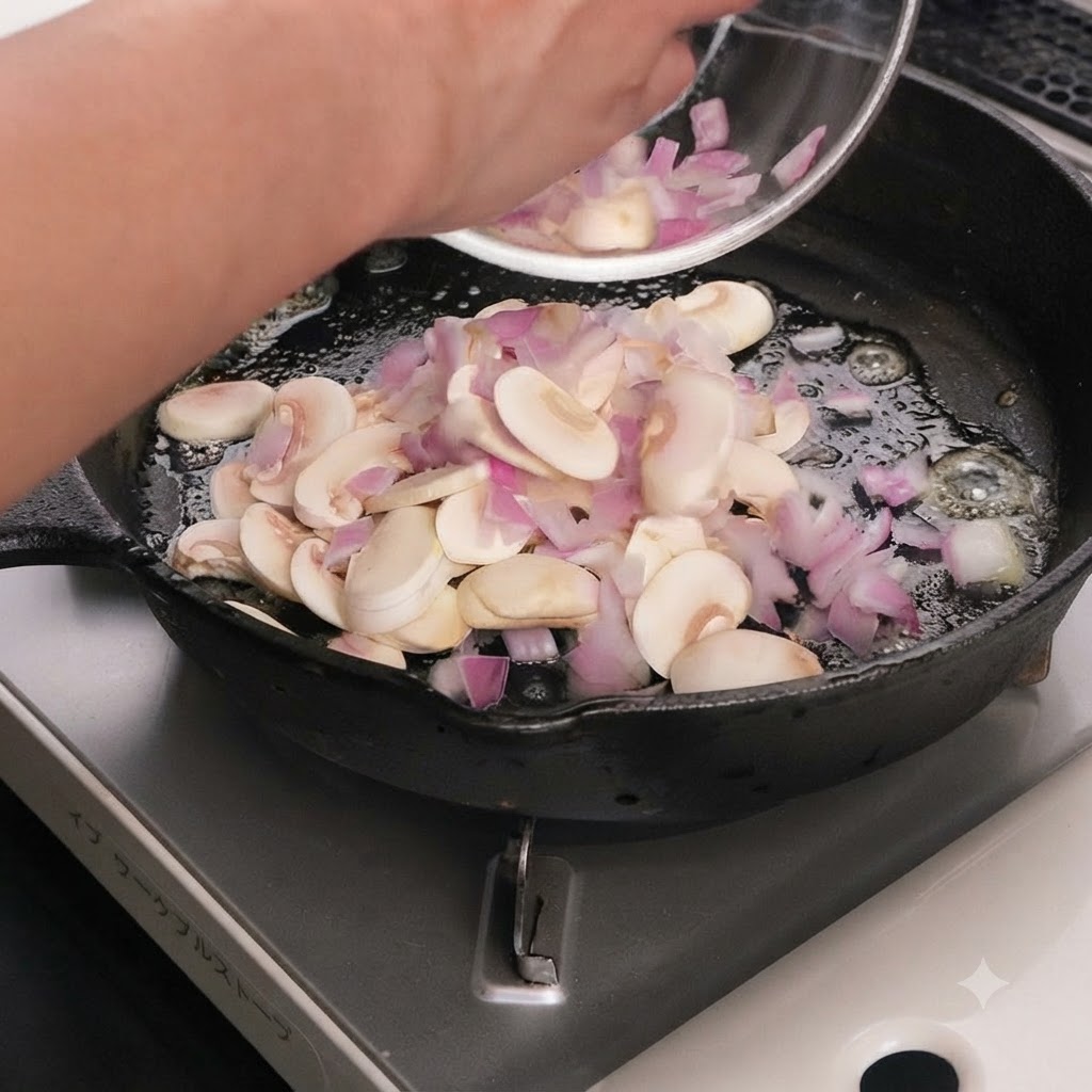 Sliced mushrooms and red onions cooking in melted butter inside a cast iron skillet.
