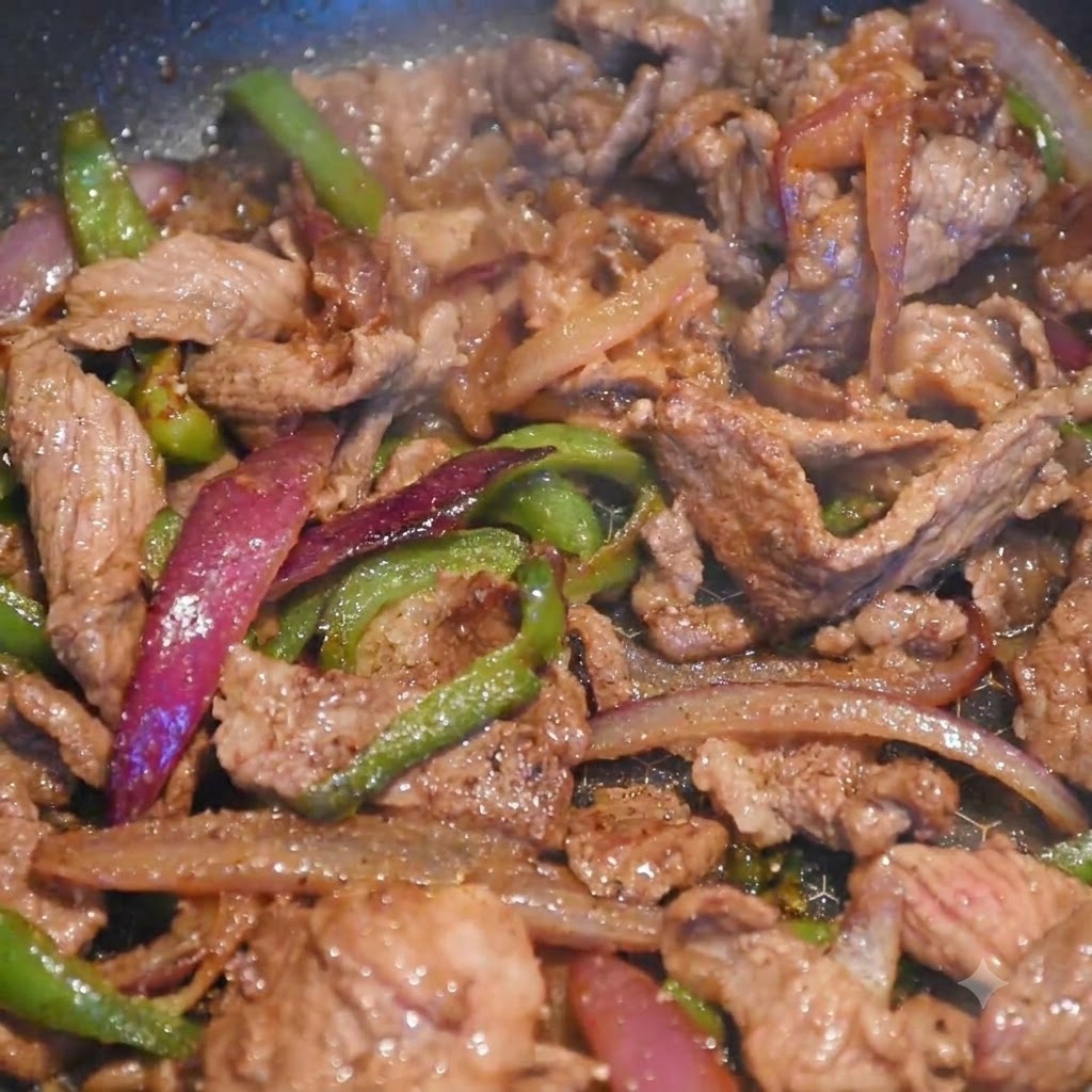 Beef and colorful vegetable strips cooking together in a skillet as seasoning is added.