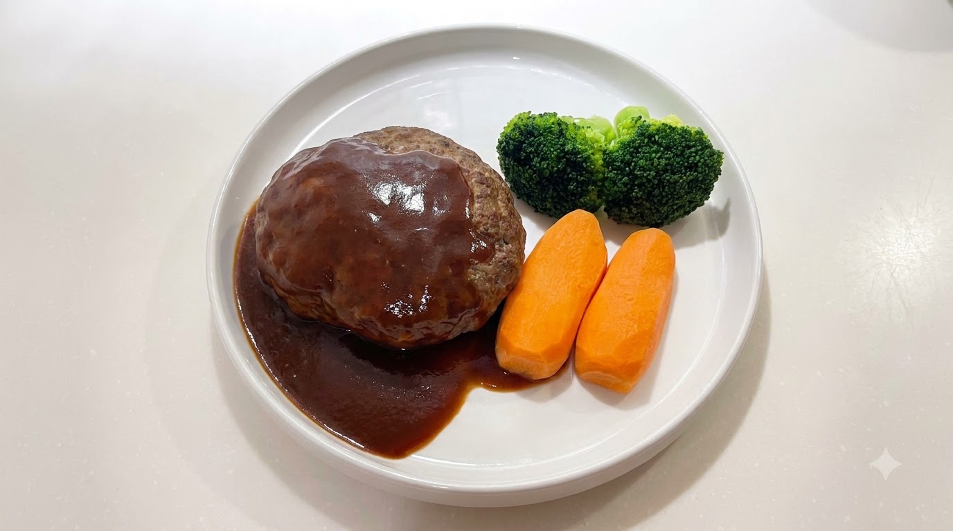A juicy Japanese Hamburg steak smothered in glossy dark brown sauce, served alongside carrots and broccoli