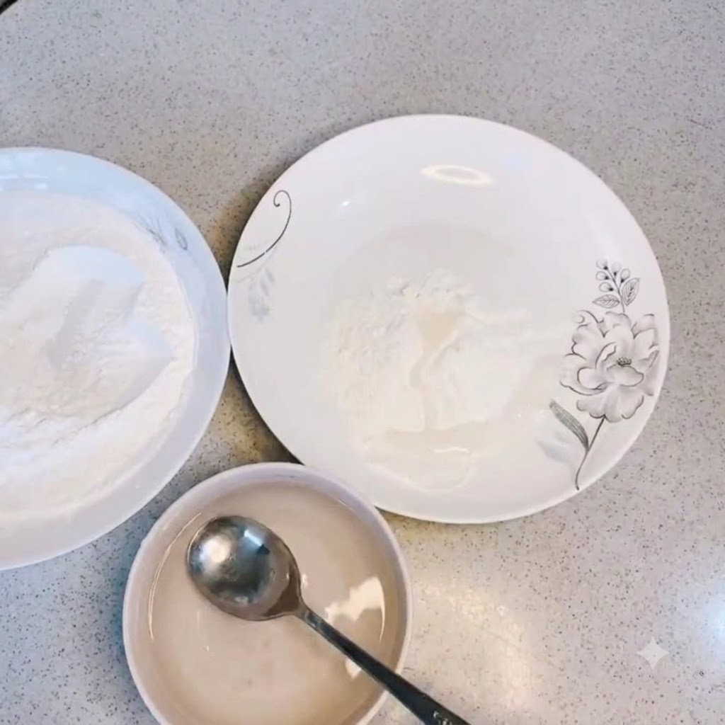 Plain water being poured into a bowl of dry frying powder and stirred with a spoon.