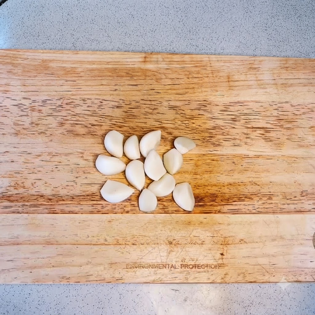 Garlic cloves arranged on a wooden cutting board ready to be minced.